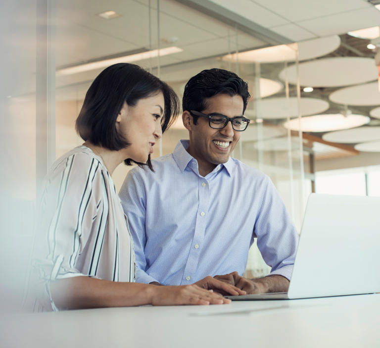 Two business people looking at a laptop and smiling.