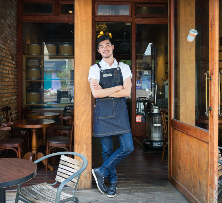 A proud small business owner standing in front of his café.